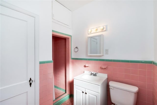 bathroom with vanity, tile walls, and toilet