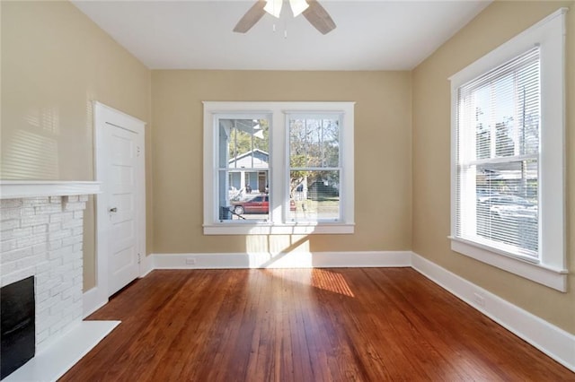 unfurnished living room featuring hardwood / wood-style floors, plenty of natural light, ceiling fan, and a fireplace