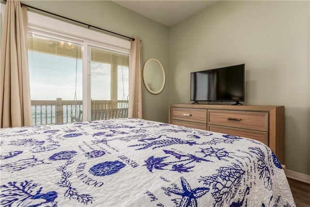 bedroom featuring a water view, access to exterior, baseboards, and wood finished floors