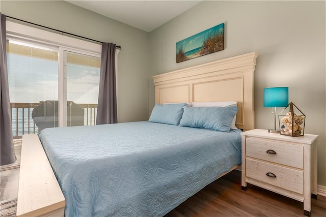 bedroom with dark wood-style floors, access to outside, and a water view