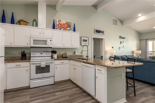 kitchen featuring a peninsula, white appliances, a sink, white cabinets, and open floor plan