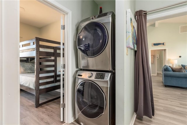 laundry area featuring laundry area, visible vents, light wood-style floors, and stacked washer / drying machine