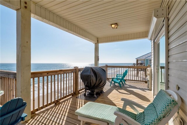 wooden deck featuring a view of the beach and a water view