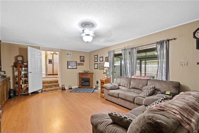 living room with ceiling fan, ornamental molding, a textured ceiling, and hardwood / wood-style floors