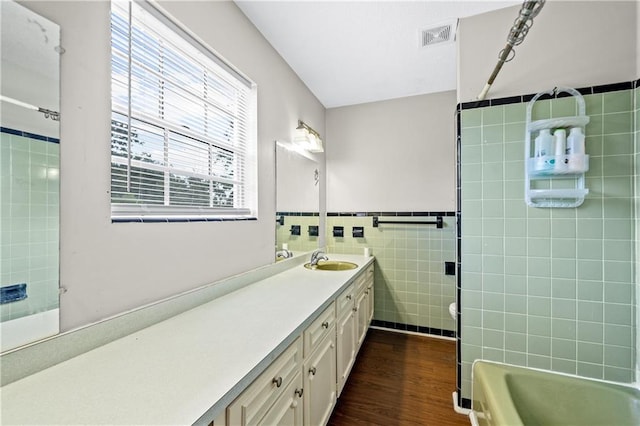 bathroom with wood-type flooring, tile walls, and vanity