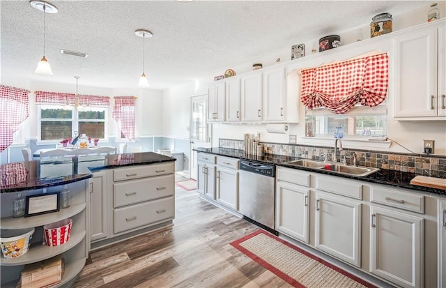 kitchen with sink, light hardwood / wood-style flooring, dishwasher, white cabinetry, and hanging light fixtures