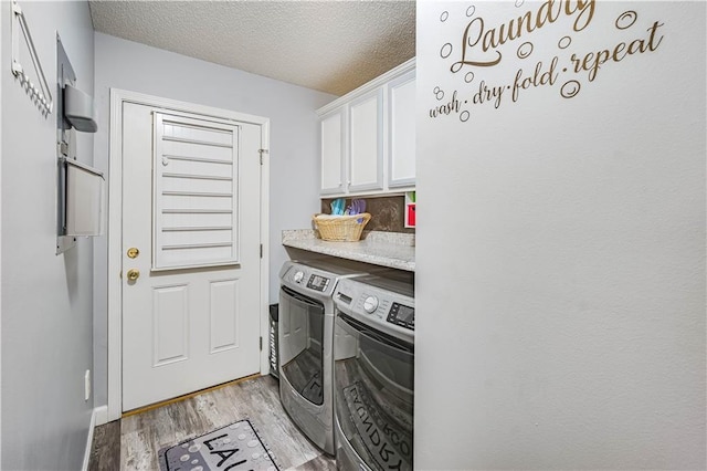 laundry room with washer and clothes dryer, cabinets, light wood-type flooring, and a textured ceiling