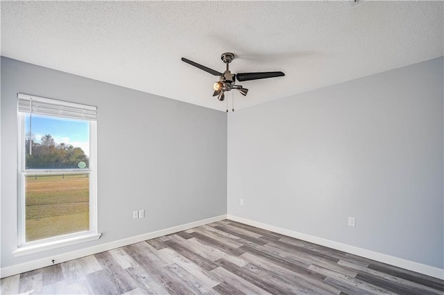 empty room featuring ceiling fan, wood-type flooring, and a textured ceiling