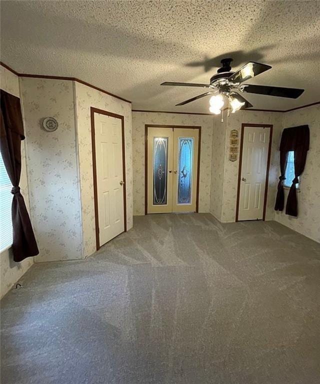 unfurnished bedroom with french doors, ornamental molding, a textured ceiling, ceiling fan, and carpet floors