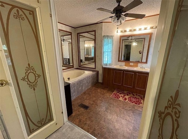 bathroom featuring a textured ceiling, vanity, tiled bath, and ornamental molding