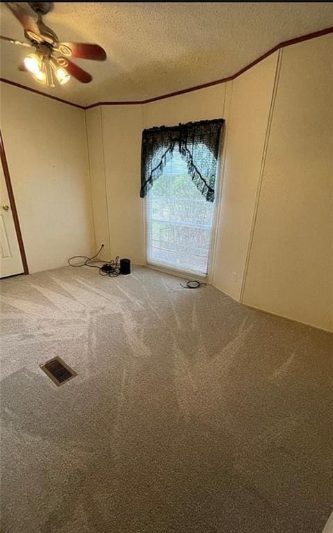 carpeted spare room with a textured ceiling and ceiling fan