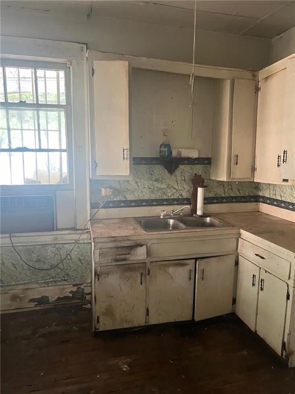 kitchen with backsplash, sink, and dark wood-type flooring