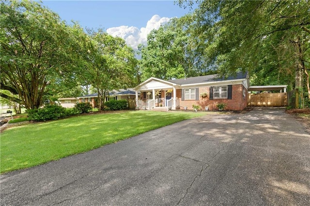 ranch-style house featuring a front yard, a carport, and covered porch