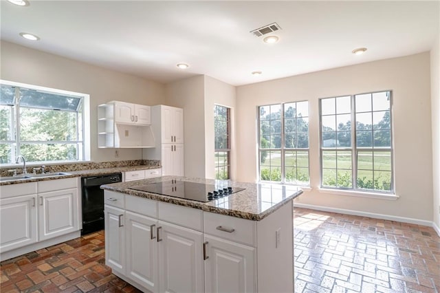 kitchen with stone countertops, a center island, sink, black appliances, and white cabinets