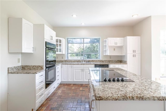 kitchen featuring black appliances, sink, light stone counters, and white cabinetry