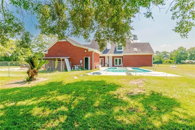 back of house with a fenced in pool and a yard