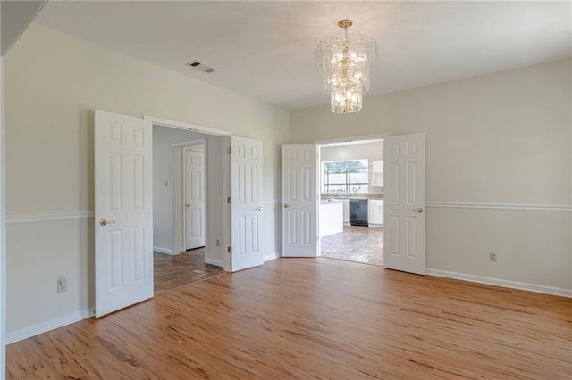 unfurnished room with light hardwood / wood-style flooring and an inviting chandelier