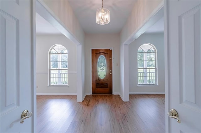 foyer entrance featuring a notable chandelier, light hardwood / wood-style floors, and a healthy amount of sunlight