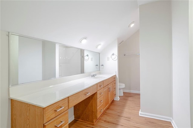 bathroom featuring wood-type flooring, vanity, vaulted ceiling, and toilet