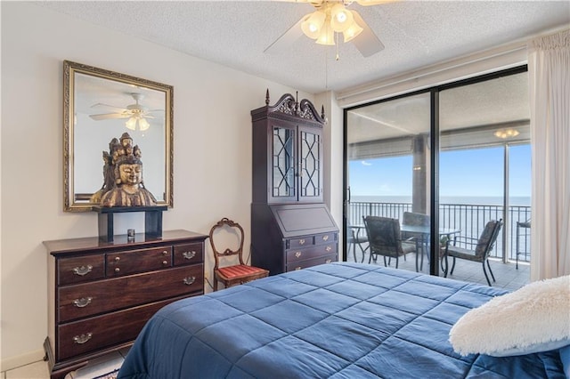 bedroom with a water view, a textured ceiling, access to exterior, and ceiling fan