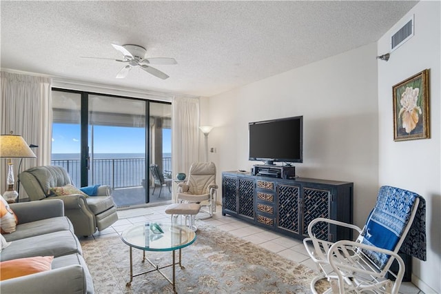 tiled living room with a textured ceiling, ceiling fan, and a water view