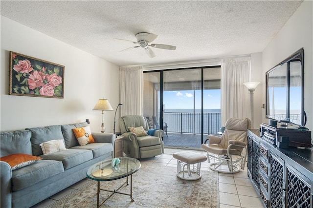 tiled living room with plenty of natural light, a textured ceiling, ceiling fan, and a water view