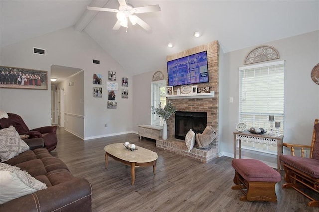 living room featuring high vaulted ceiling, hardwood / wood-style flooring, ceiling fan, a brick fireplace, and beam ceiling