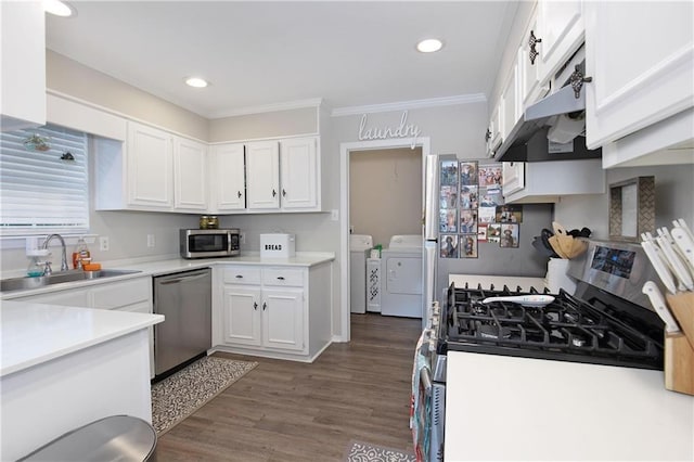 kitchen with dark wood-type flooring, sink, appliances with stainless steel finishes, washer and clothes dryer, and white cabinets