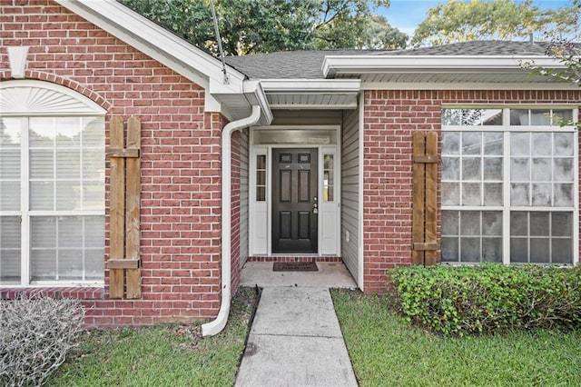 property entrance with a shingled roof and brick siding