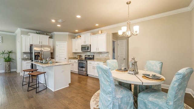 10580 Relic Rd S, Mobile, AL 36608 - kitchen with stainless steel appliances, crown molding, decorative backsplash, a chandelier, and white cabinetry