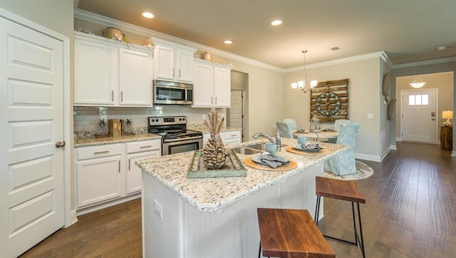 10580 Relic Rd S, Mobile, AL 36608 - kitchen featuring stainless steel appliances, backsplash, white cabinets, dark wood finished floors, and an island with sink