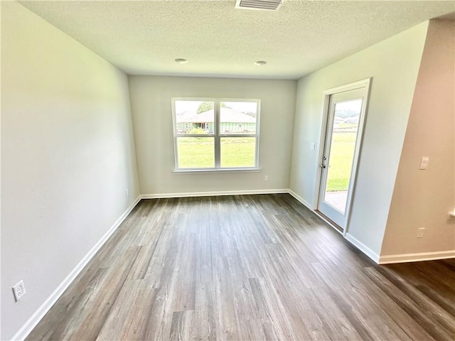 spare room with a textured ceiling and hardwood / wood-style flooring