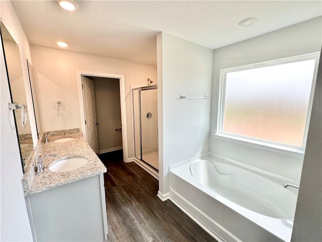 bathroom with hardwood / wood-style floors, vanity, shower with separate bathtub, and a textured ceiling