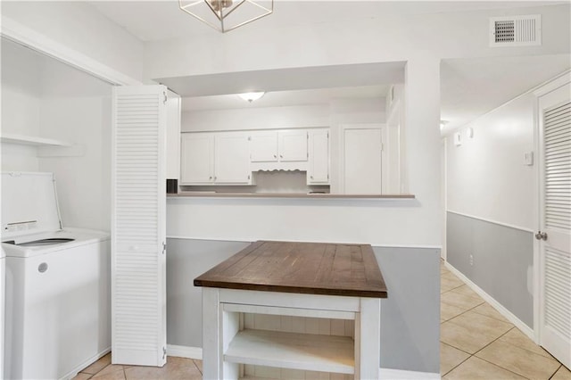 kitchen featuring white cabinetry, washer / clothes dryer, and light tile patterned floors