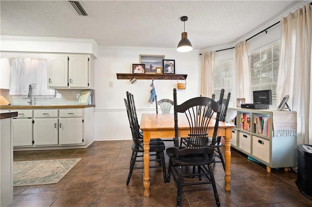 dining space with visible vents, baseboards, a textured ceiling, and dark tile patterned floors