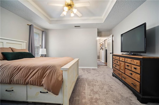 bedroom with visible vents, light colored carpet, a raised ceiling, and ornamental molding