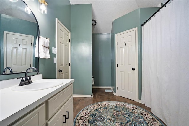 full bath featuring vanity, baseboards, tile patterned flooring, a textured ceiling, and toilet