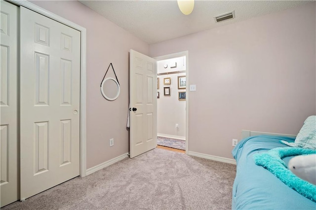 bedroom with light carpet, a textured ceiling, and baseboards