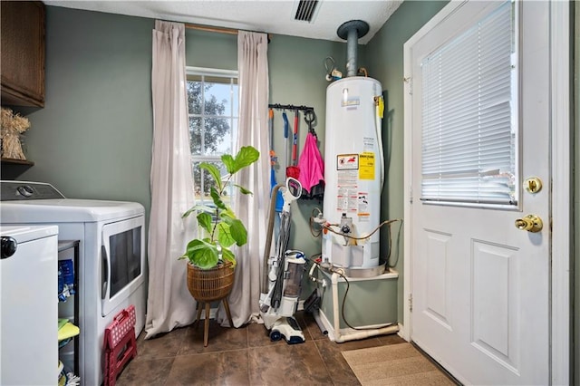 clothes washing area with visible vents, water heater, cabinet space, tile patterned flooring, and washing machine and clothes dryer