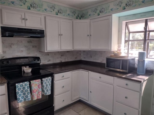 829 Desoto Dr, Dauphin Island, AL 36528 - kitchen with black range with electric stovetop, stainless steel microwave, range hood, and white cabinets