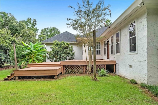 back of property featuring a wooden deck and a lawn