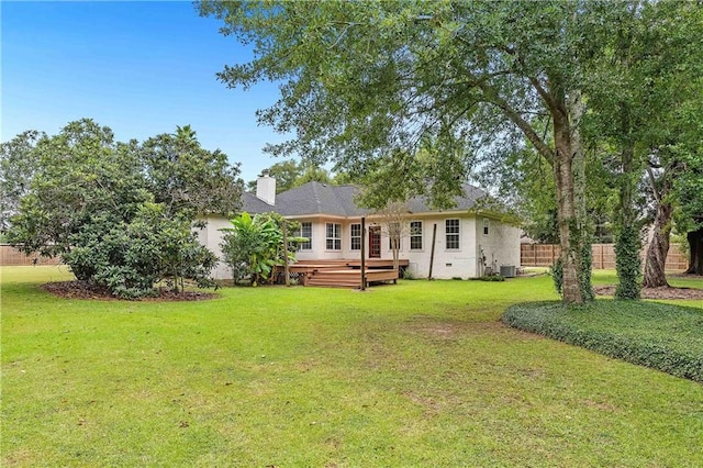 back of property with central AC unit, a wooden deck, and a lawn