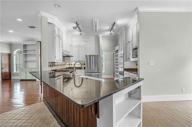 kitchen with a healthy amount of sunlight, white cabinets, track lighting, wood-type flooring, and stainless steel fridge