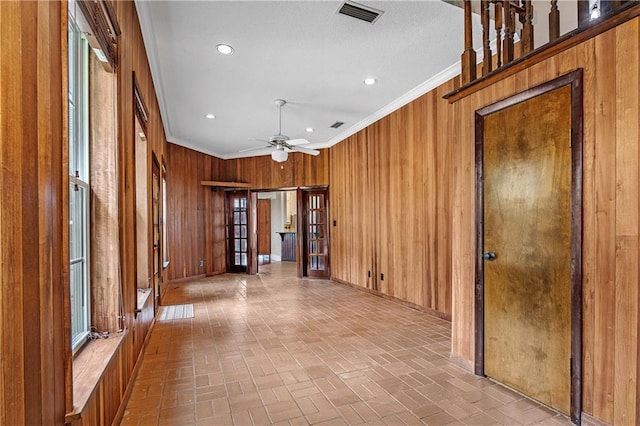 hall with wooden walls, french doors, and crown molding