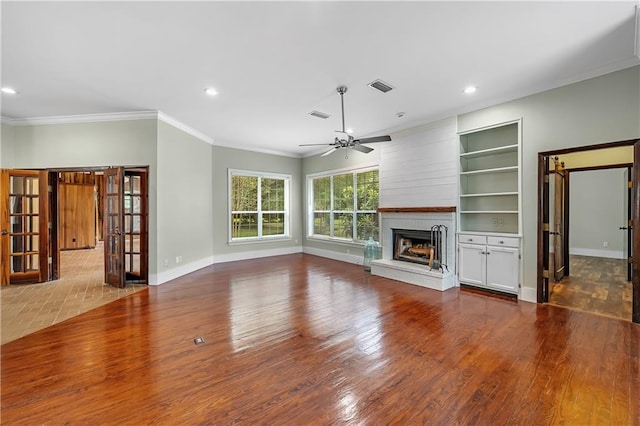 unfurnished living room with hardwood / wood-style flooring, ornamental molding, a large fireplace, and ceiling fan