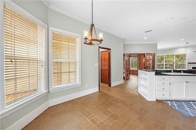 kitchen featuring sink, hanging light fixtures, a notable chandelier, crown molding, and white cabinets