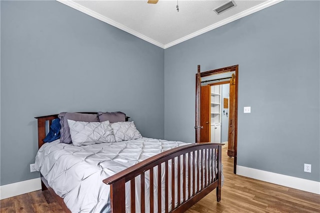 bedroom with hardwood / wood-style floors, ornamental molding, and ceiling fan