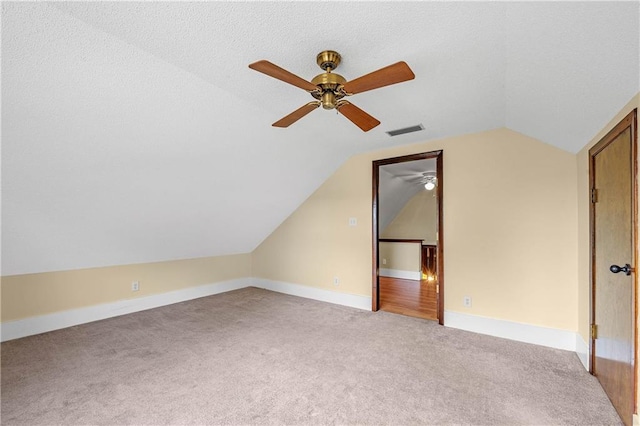 additional living space with ceiling fan, carpet floors, lofted ceiling, and a textured ceiling