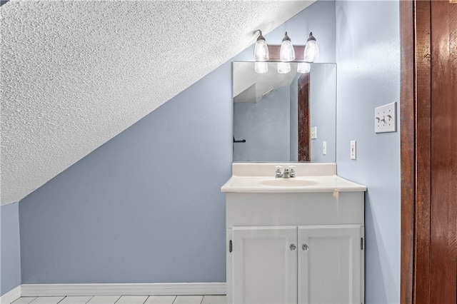 bathroom featuring tile patterned flooring, vaulted ceiling, a textured ceiling, and vanity