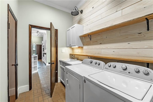 washroom with wood walls, washing machine and clothes dryer, sink, and cabinets